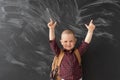 schoolboy stands near the blackboard. Place for text. Point with your index fingers up. Place for text.