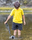 A schoolboy stands in the river on outdooor and destroys a mirrorless photo camera