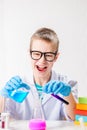 A schoolboy studies multi-colored substances in test tubes, conducts experiments - a portrait on a white background. Royalty Free Stock Photo