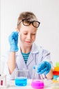 A schoolboy studies multi-colored substances in test tubes, conducts experiments - a portrait on a white background.