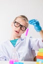 A schoolboy studies multi-colored substances in test tubes, conducts experiments - a portrait on a white background. Royalty Free Stock Photo