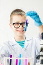 A schoolboy studies multi-colored substances in test tubes, conducts experiments - a portrait on a white background. Concept for Royalty Free Stock Photo