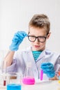 A schoolboy studies multi-colored substances in test tubes, conducts experiments - a portrait on a white background. Royalty Free Stock Photo