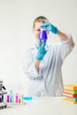 A schoolboy studies multi-colored substances in test tubes, conducts experiments - a portrait on a white background. Royalty Free Stock Photo