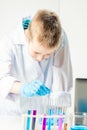 A schoolboy studies multi-colored substances in test tubes, conducts experiments - a portrait on a white background. Royalty Free Stock Photo