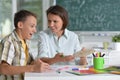 Portrait of Schoolboy and teacher sitting at classroom Royalty Free Stock Photo