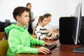 Schoolboy using computer at lesson, teacher teaching pupils in class room Royalty Free Stock Photo