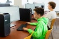 Schoolboy using computer at lesson, teacher teaching pupils in class room Royalty Free Stock Photo