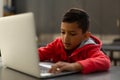 Schoolboy using laptop at desk in a classroom