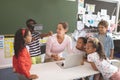 Schoolboy using virtual reality headset at school in classroom with his classmates and her teacher n Royalty Free Stock Photo