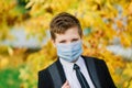 Schoolboy walks out of school wearing protective mask in a city