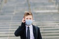 Schoolboy walks out of school wearing protective mask in a city