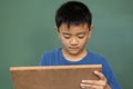 Schoolboy writing on chalk slate against green chalkboard in a classroom Royalty Free Stock Photo