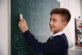 Schoolboy writing chemical formulas on chalkboard Royalty Free Stock Photo