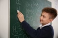 Schoolboy writing chemical formulas on chalkboard Royalty Free Stock Photo