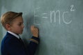 Schoolboy writing maths formula on chalkboard Royalty Free Stock Photo