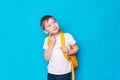 Schoolboy with a yellow backpack thought against a blue background Royalty Free Stock Photo