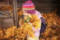 Schoolchild carries an armful of maple leaves. autumn school holiday.