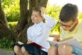 Schoolchildren doing homework, in the park in the fresh air, the girl thought about the task and scratches her head