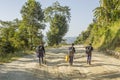 A schoolchildren girl and boys go to school on a dirt road in the forest against the backdrop of the mountains Royalty Free Stock Photo