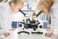 Schoolchildren in lab coats using microscopes