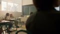 Schoolchildren sitting at desks in classroom. Schoolteacher teaching students