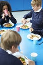 Schoolchildren Sitting At Table Eating Cooked Lunch Royalty Free Stock Photo