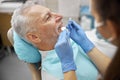 Schooled young dentist examining an elderly patient Royalty Free Stock Photo