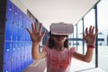 Schoolgirl anticipating while using virtual reality glasses in corridor