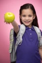 Schoolgirl with apple. Cheerful little schoolgirl holding an app