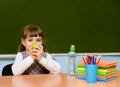 Schoolgirl with apple near chalkboard