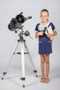 Schoolgirl astronomer is a telescope with a globe and books in the hands
