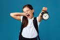 schoolgirl with backpack is holding alarm clock