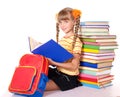 Schoolgirl with backpack reading pile of books.