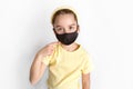 A schoolgirl in a black protective mask draws attention to the correctness and compulsory wearing of protective masks.