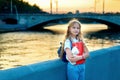 Schoolgirl blonde with blue eyes is standing near the river in the city at sunset Royalty Free Stock Photo