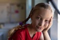 Schoolgirl with blonde hair in plaits looking to camera in an elementary school classroom Royalty Free Stock Photo