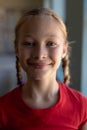 Schoolgirl with blonde hair in plaits looking to camera in an elementary school classroom Royalty Free Stock Photo