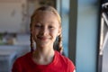 Schoolgirl with blonde hair in plaits looking to camera in an elementary school classroom Royalty Free Stock Photo