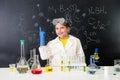 Schoolgirl in chemistry lab pointing at formula on blackboard Royalty Free Stock Photo