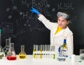 Schoolgirl in chemistry lab pointing at formula on blackboard Royalty Free Stock Photo