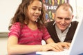 Schoolgirl In IT Class Using Computer With Teacher