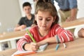 Schoolgirl in class wriitng in notebook