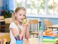 Schoolgirl in the classroom eating a green apple