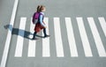 Schoolgirl crossing road on way to school. Zebra traffic walk way in the city. Concept pedestrians passing a crosswalk.  Stylish Royalty Free Stock Photo