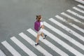 Schoolgirl crossing road on way to school. Zebra traffic walk way in the city. Concept pedestrians passing a crosswalk.  Stylish Royalty Free Stock Photo