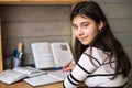 Schoolgirl does homework. Looking at the camera. Education.