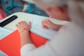 Schoolgirl doing sums in her red copybook.