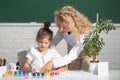 Schoolgirl drawing with teacher. Children from elementary school study at draw lesson. Teacher and little students Royalty Free Stock Photo