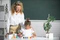 Schoolgirl drawing with teacher. Children from elementary school study at draw lesson. Pupil girl with mother teacher Royalty Free Stock Photo